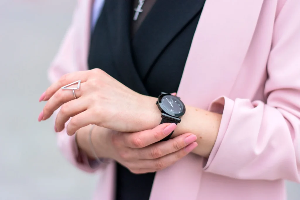 Zbliżenie na stylową kobietę dopasowującą zegarek na rękę, prezentującą elegancję i nowoczesną modę.