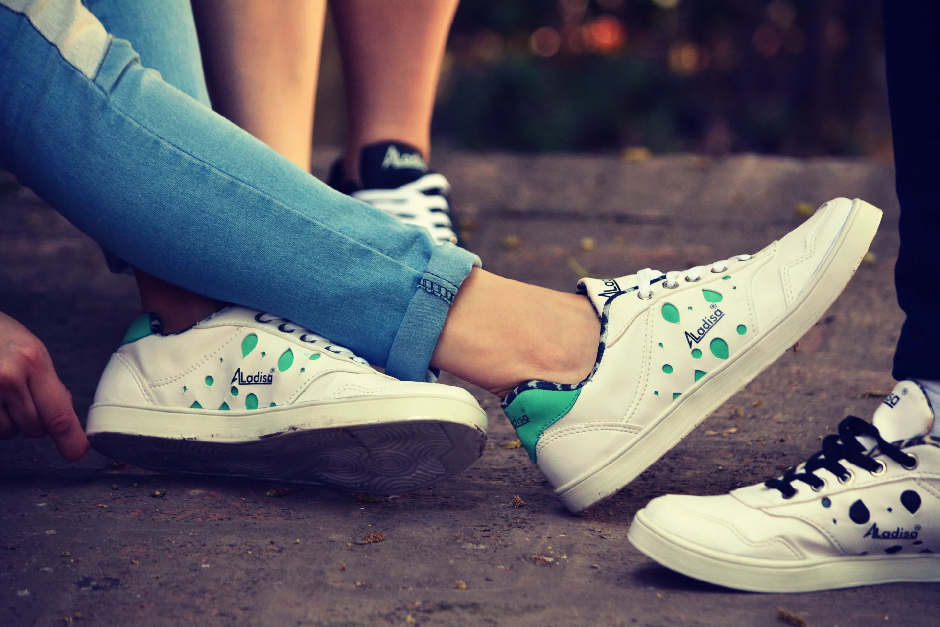 Grupa osób odpoczywająca na zewnątrz, ubrana w modne, codzienne sneakersy, w swobodnej pozie.